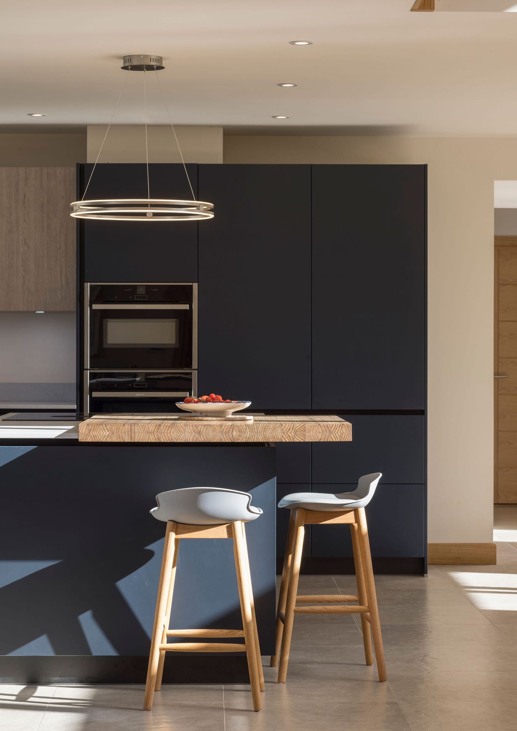 Modern kitchen island with dark cabinetry and two wooden bar stools