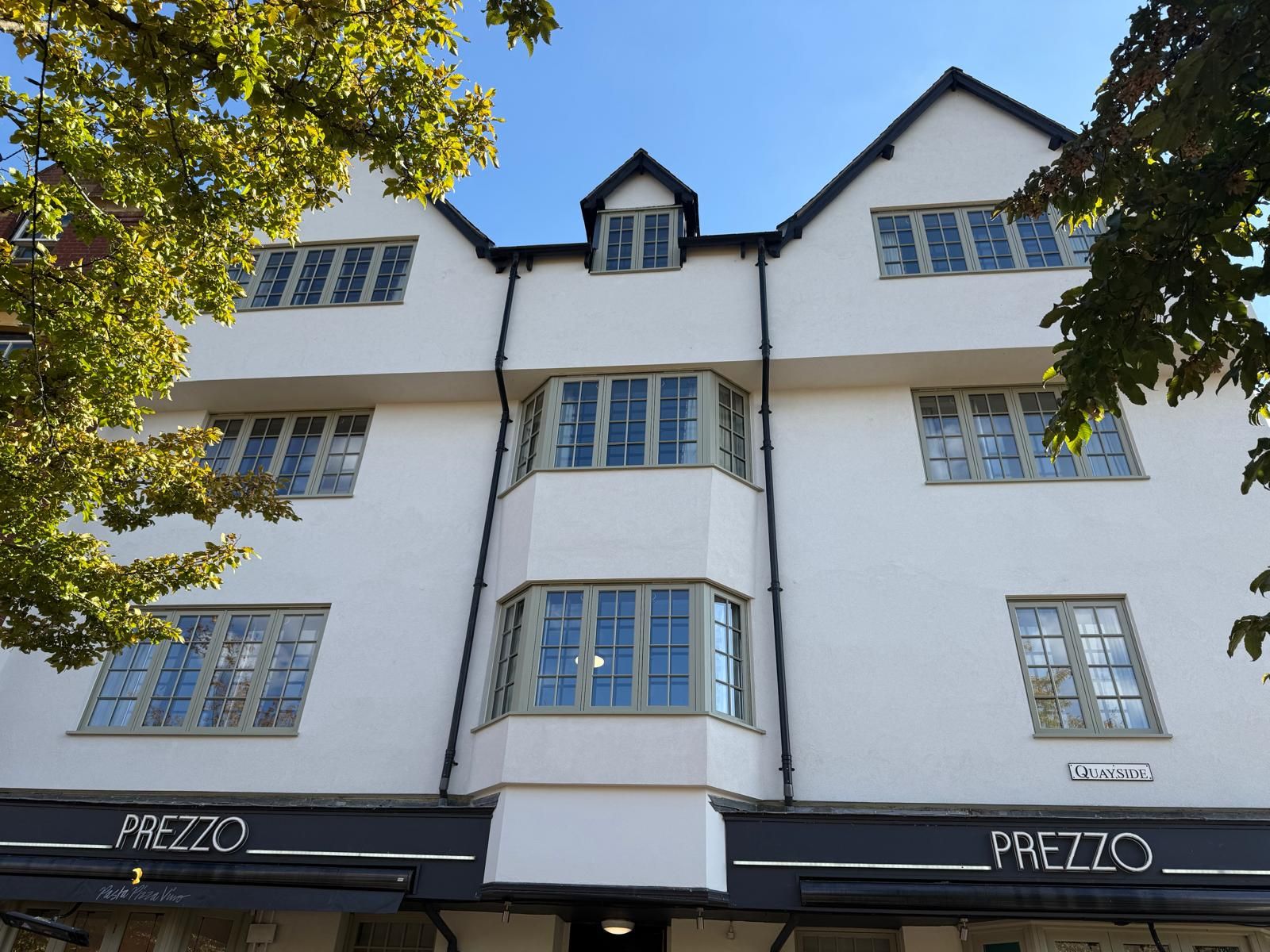 Close-up of finished white render and new sage-green timber windows at Basing House