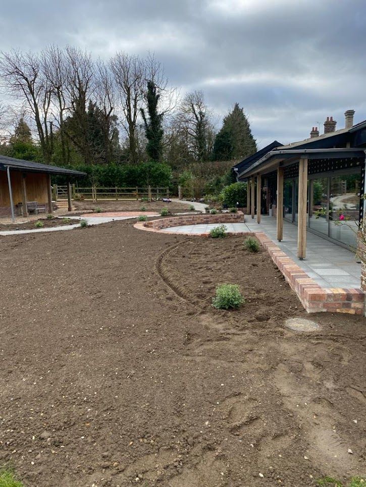 Rear garden mid-landscaping with bare soil beside the barn extension