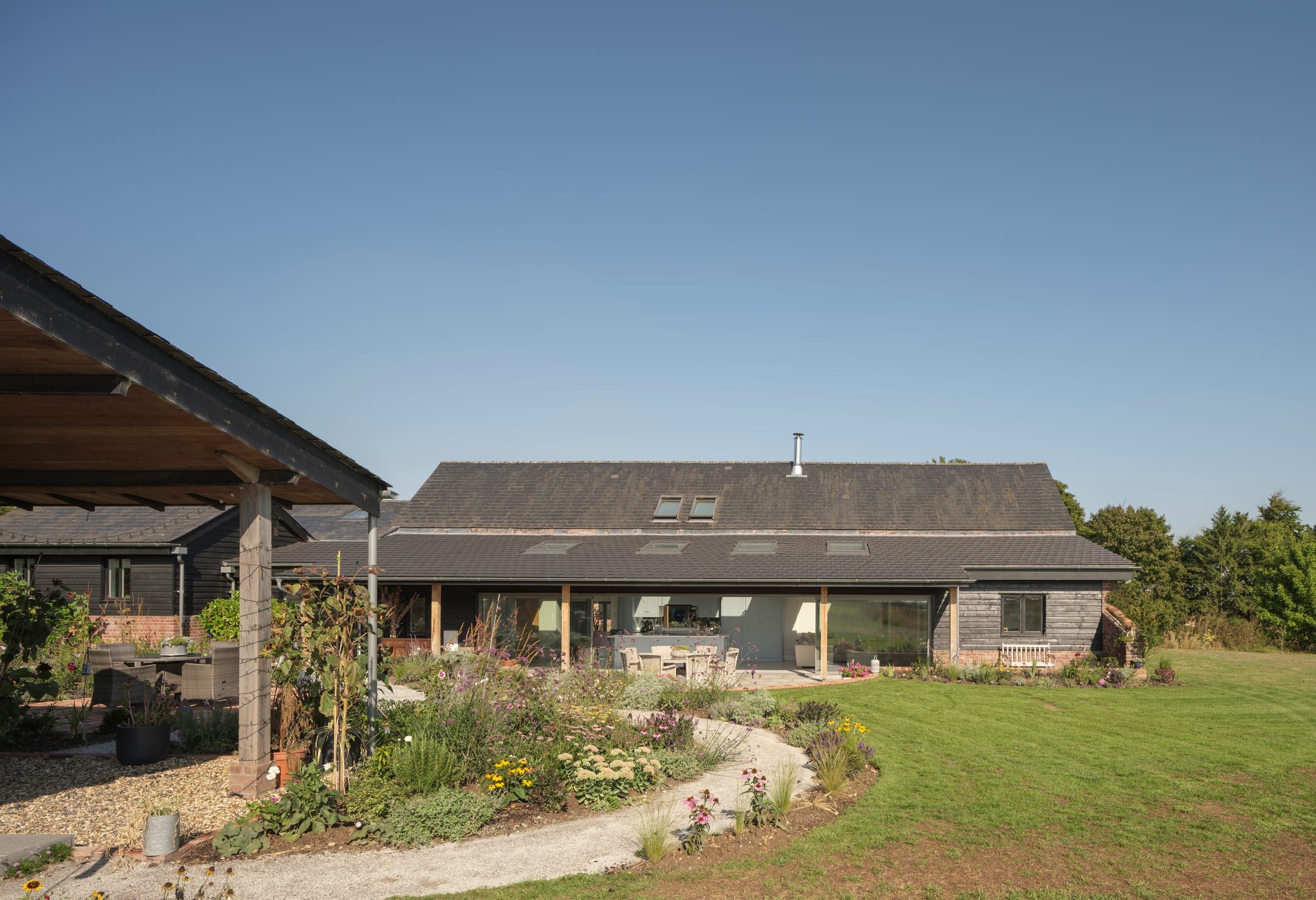 Black timber-clad barn extension with glazed doors opening onto garden
