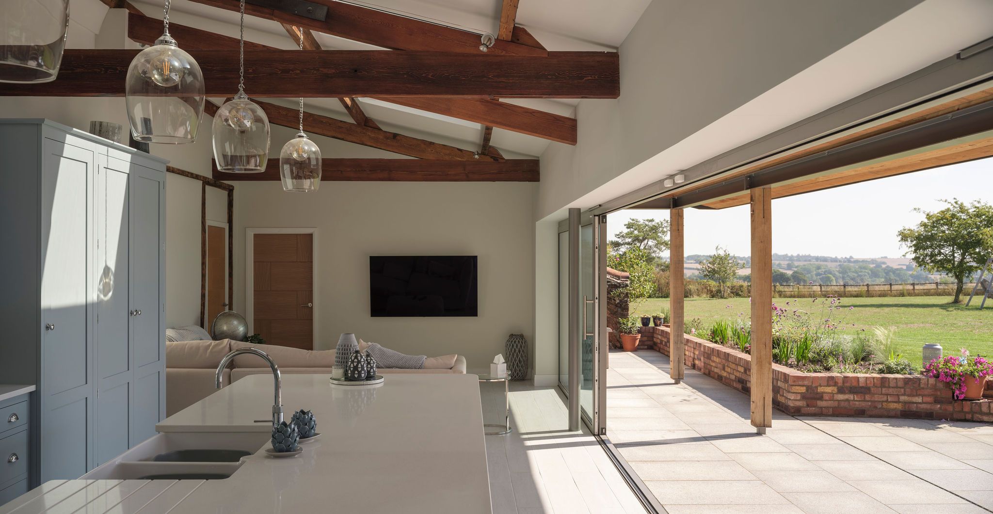 Open-plan kitchen with exposed oak beams and sliding doors open to the garden