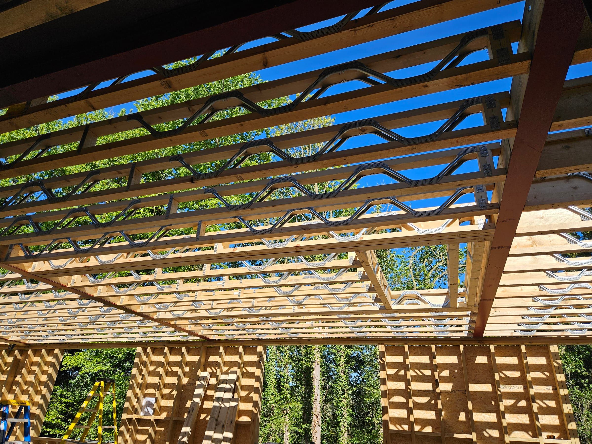 Open barn roof structure with timber posi-joist trusses against blue sky