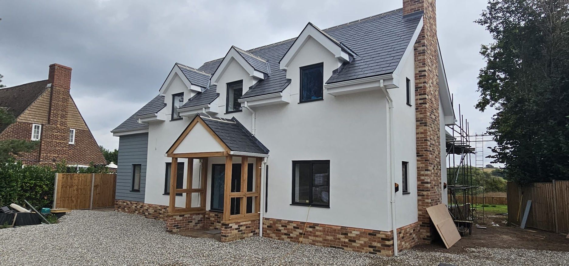 Completed white render new build with dormer windows and oak-framed porch
