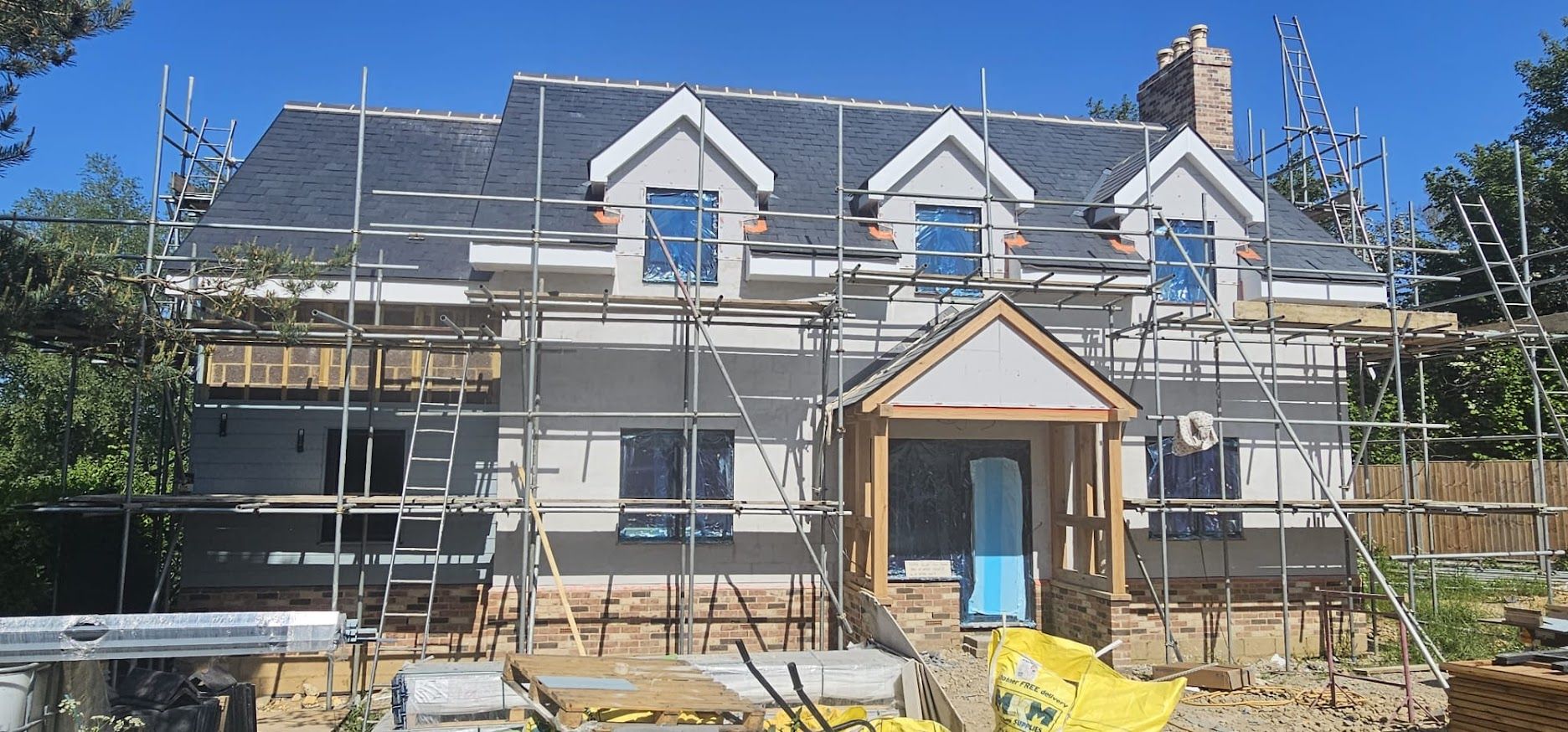 New build house under scaffolding with render finish and three dormer windows