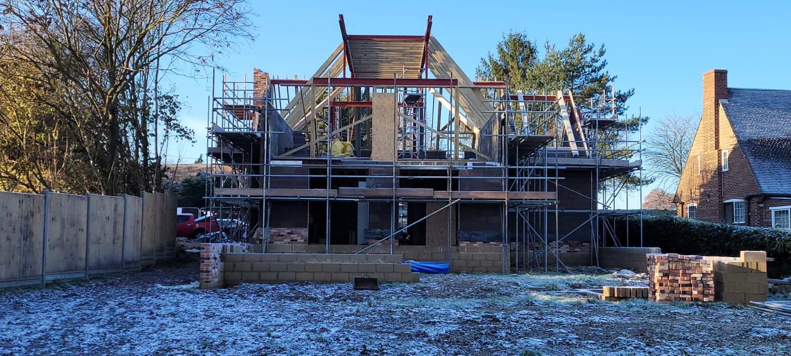 House frame with steel portal and timber roof trusses under construction in winter