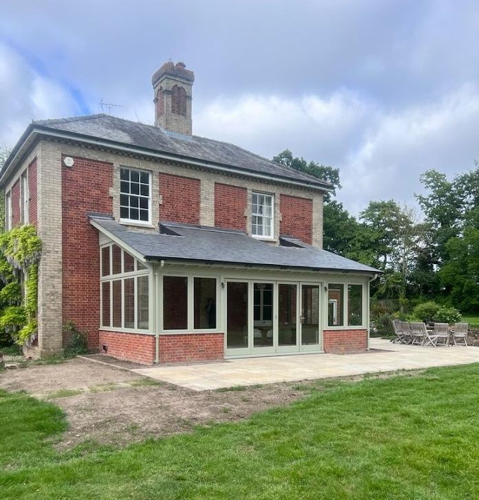 Single-storey glazed gable extension with sage green window frames