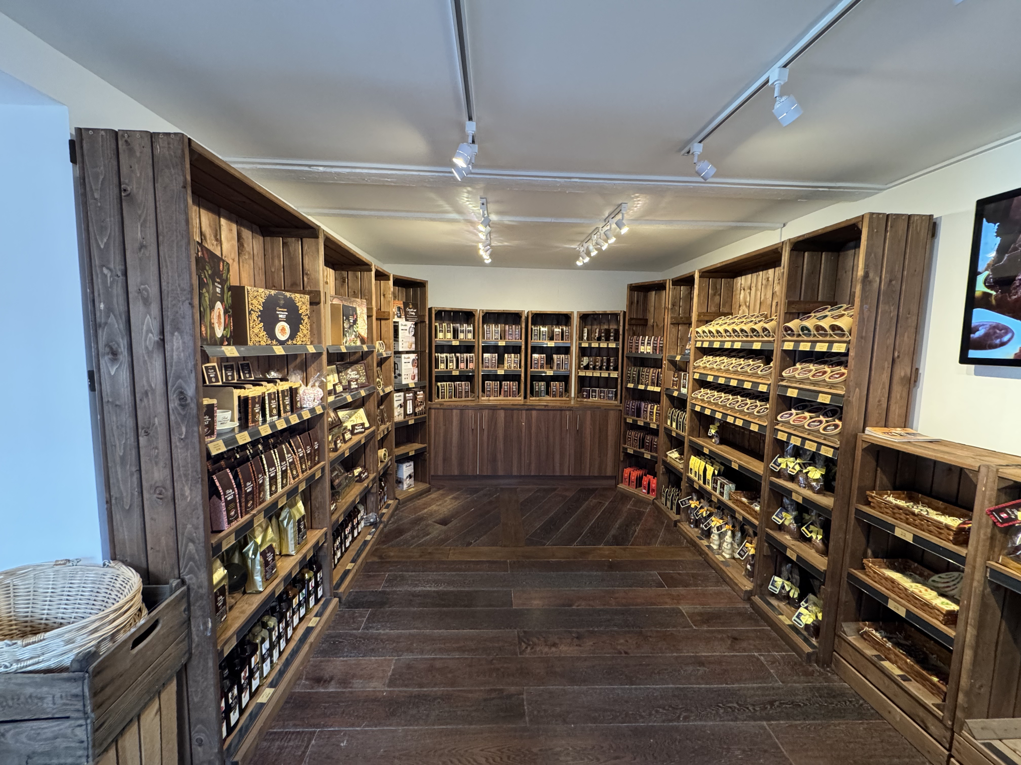 Chocolate shop interior with wooden crate-style retail shelving and dark wood flooring