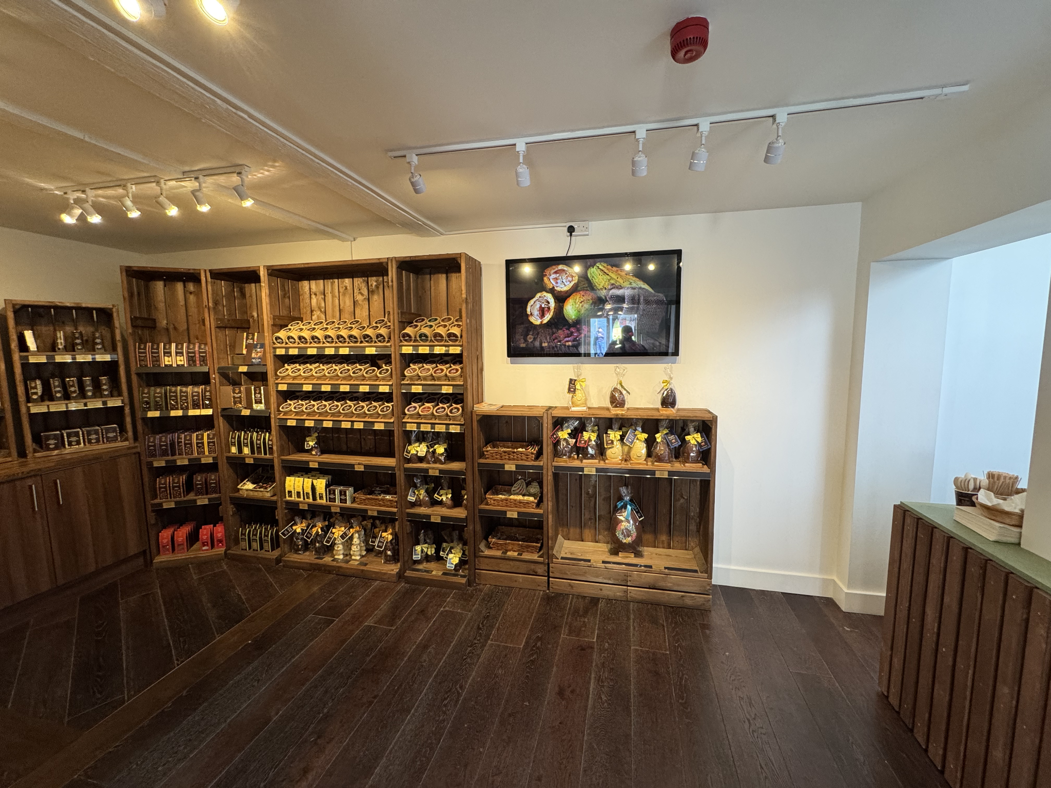 Chocolate shop shelving units with wall-mounted screen and gift-wrapped Easter chocolates