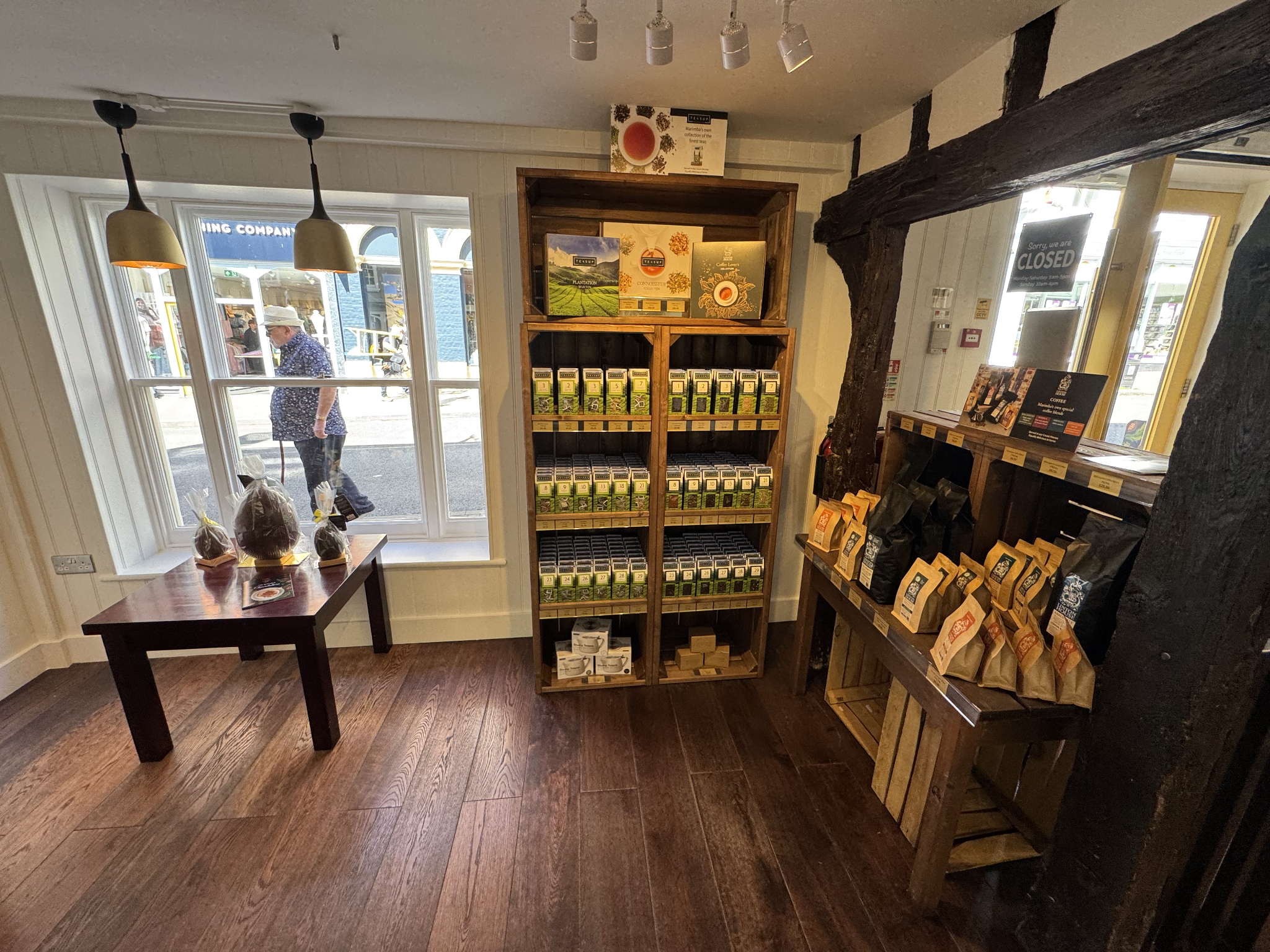 Wooden shelving displaying boxed teas and coffee bags near shop front window