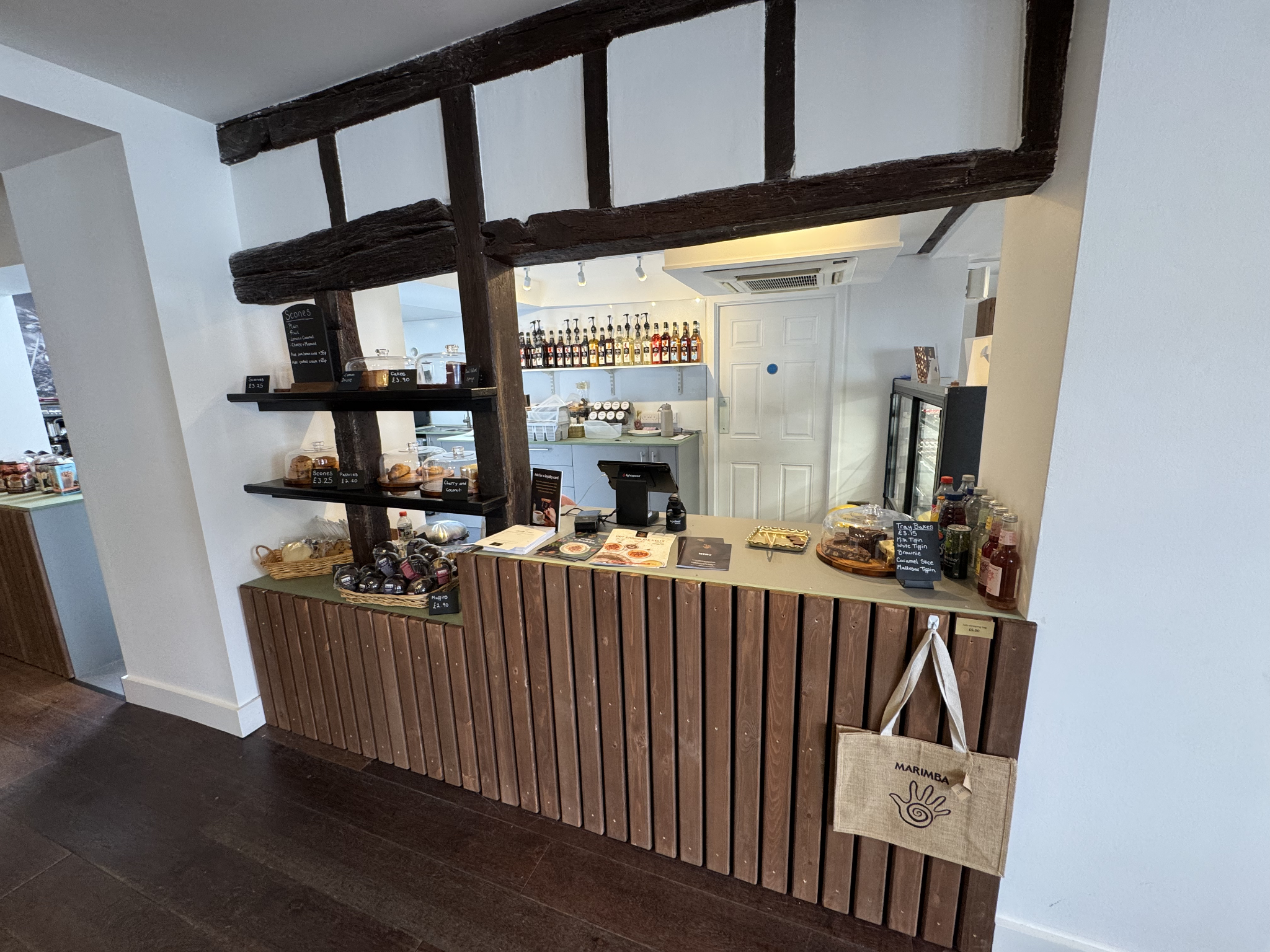Shop counter with till, cake displays and exposed timber beams under menu boards