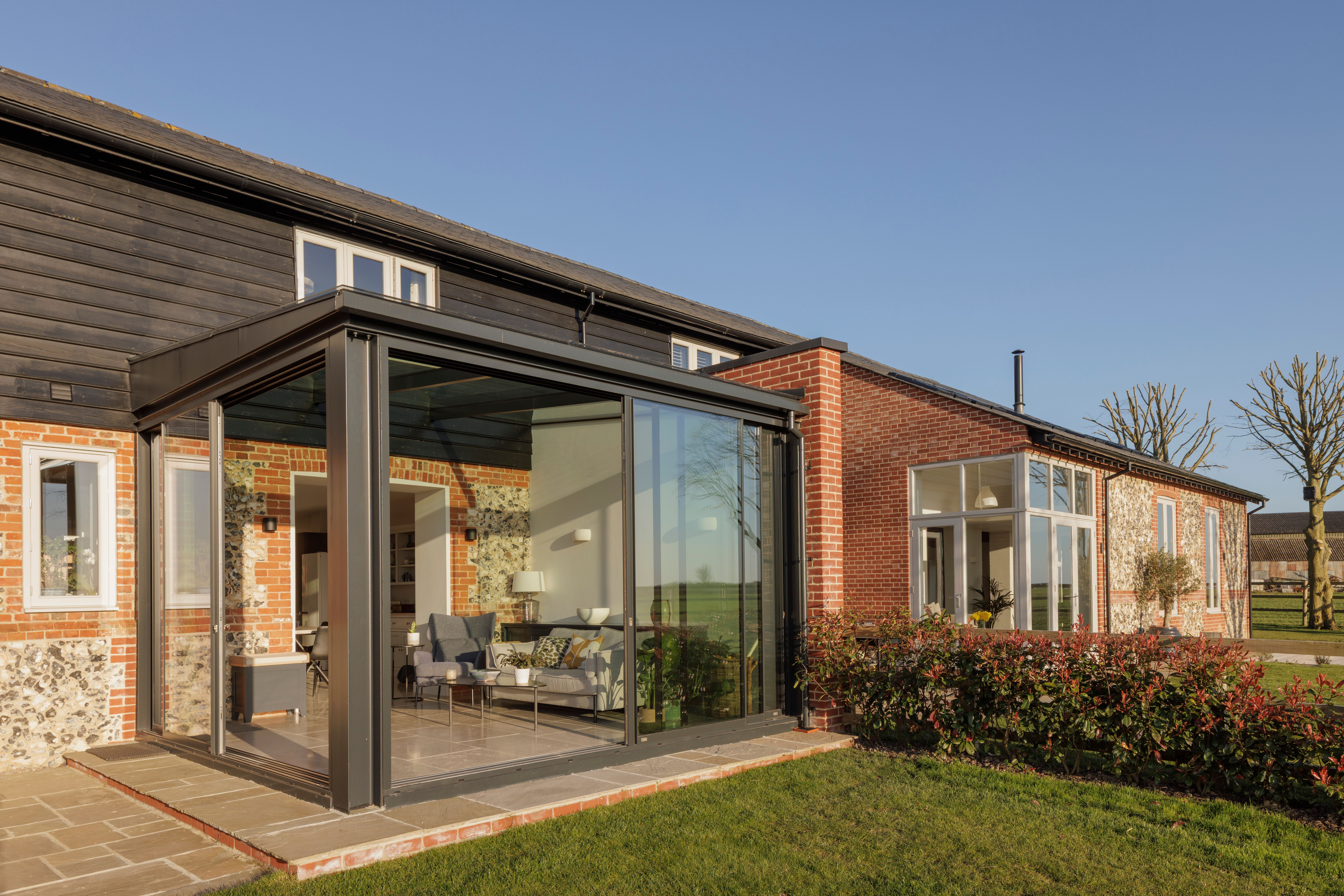 Glazed garden room extension on a brick, flint and weatherboarded barn conversion