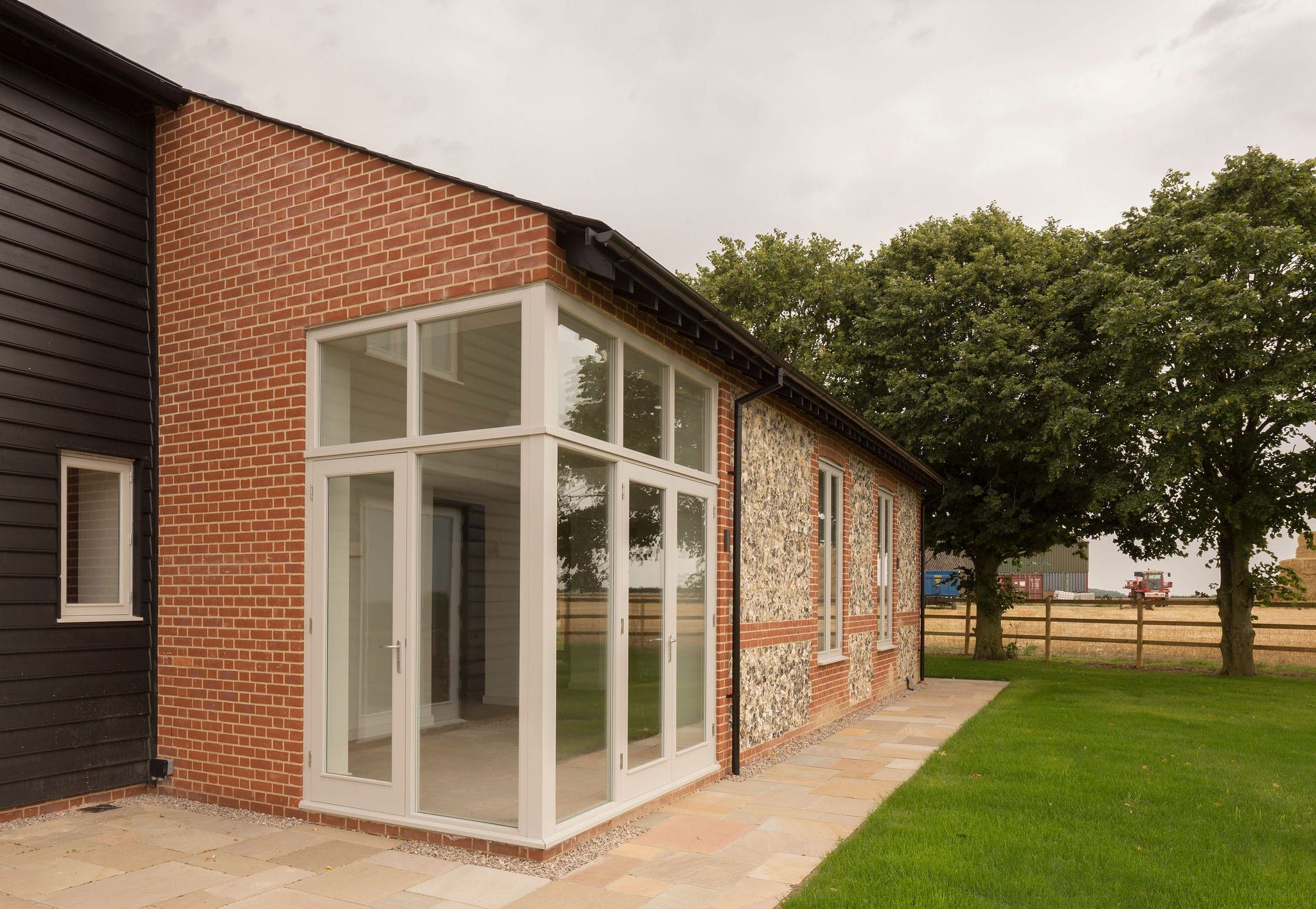 Brick and flint barn extension with a full-height glazed corner and French doors