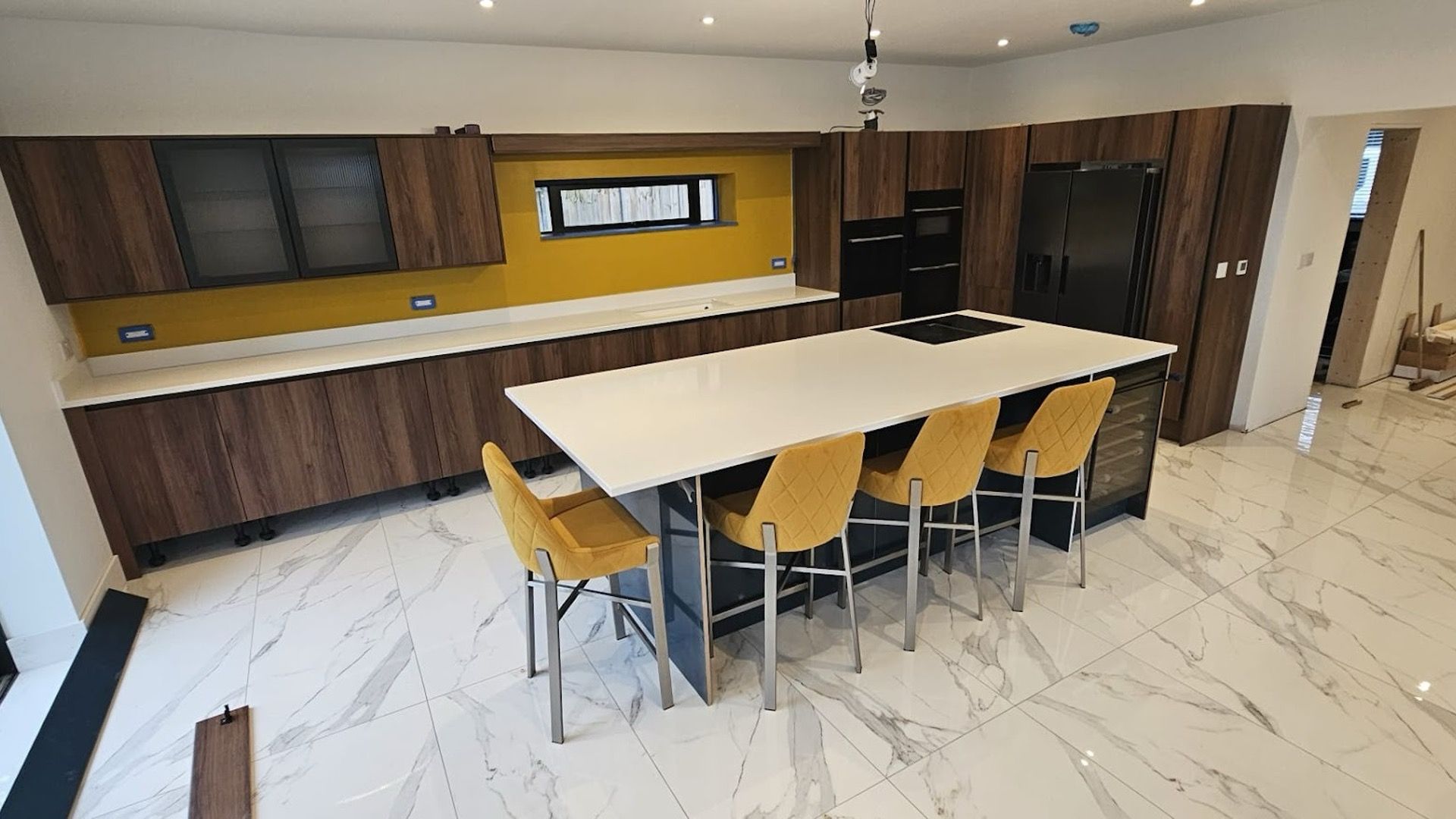Finished new build kitchen with island, bar stools and yellow splashback