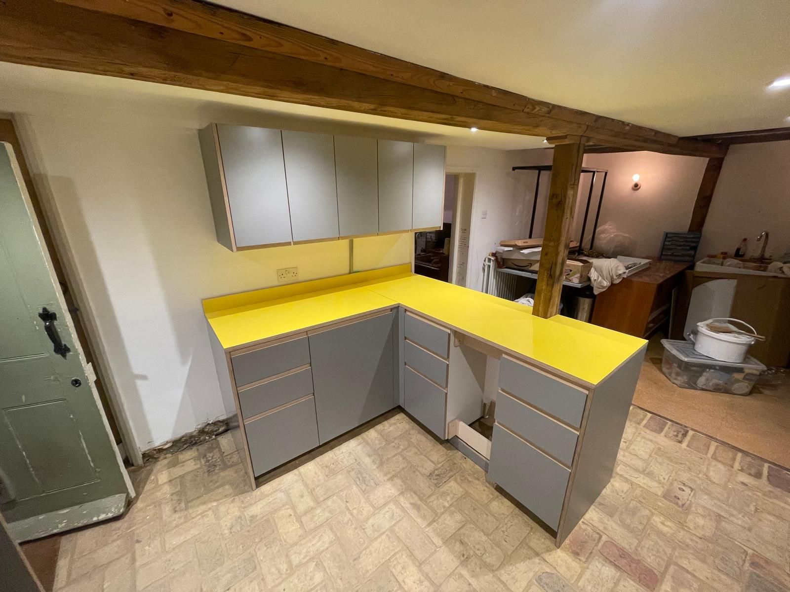 Grey kitchen units with yellow worktop during fit-out
