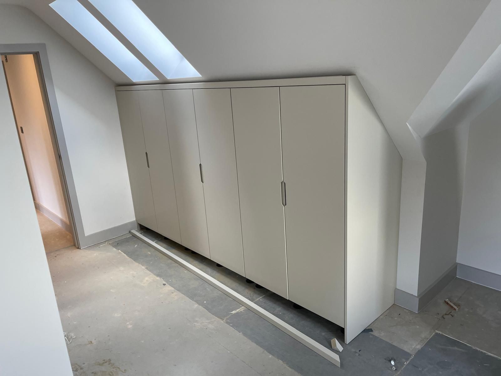 Fitted wardrobes built into sloped loft bedroom ceiling