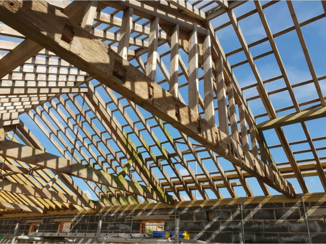 Oak roof truss framework under construction against blue sky