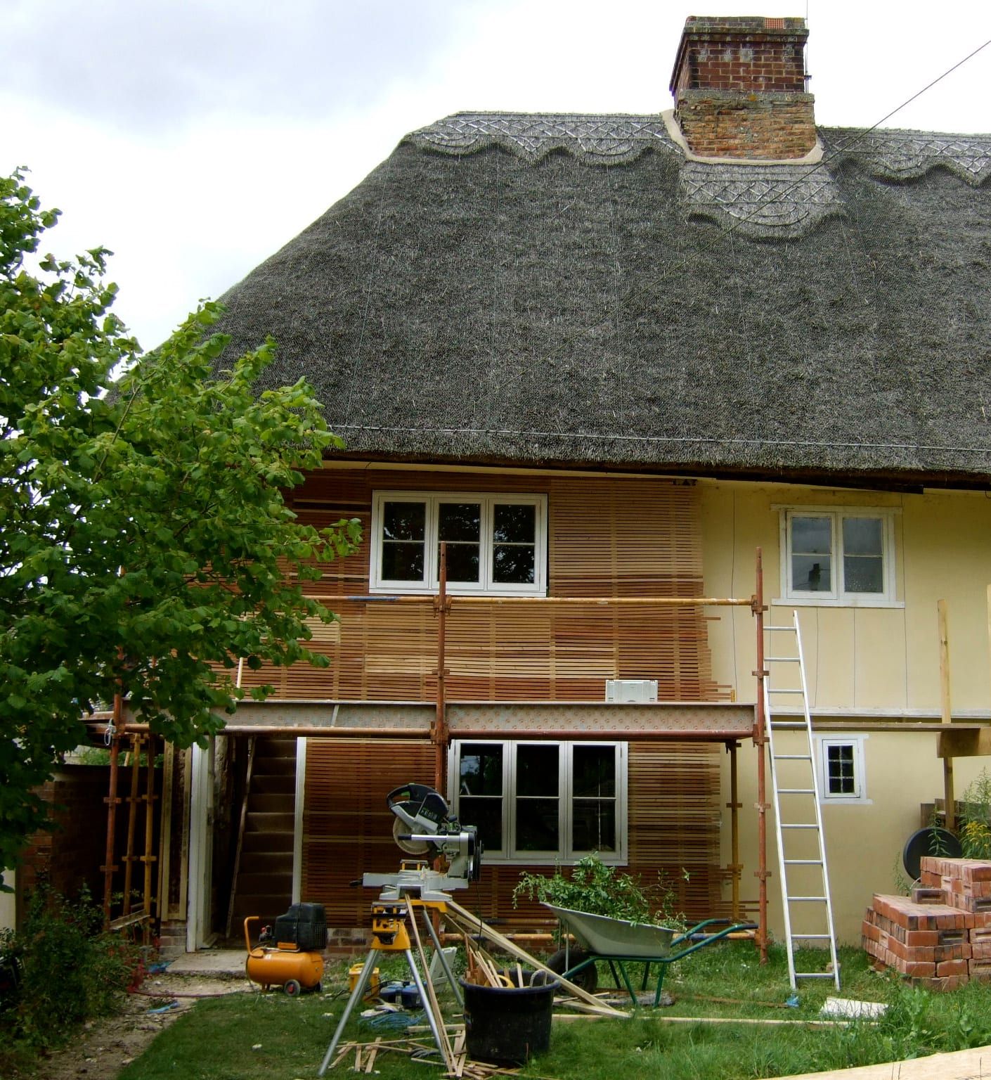 Thatched cottage exterior mid-restoration with new cedar cladding and windows